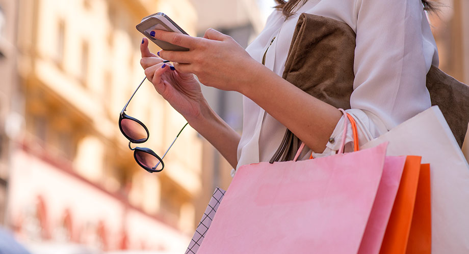 Woman holding smartphone and shopping bags