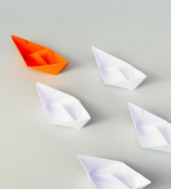 orange colored paper boat leading a white paper boats